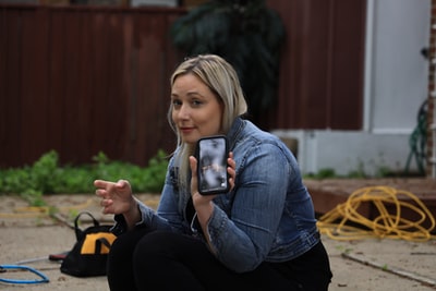 Dressed in a blue denim jacket, handheld smartphone black woman
